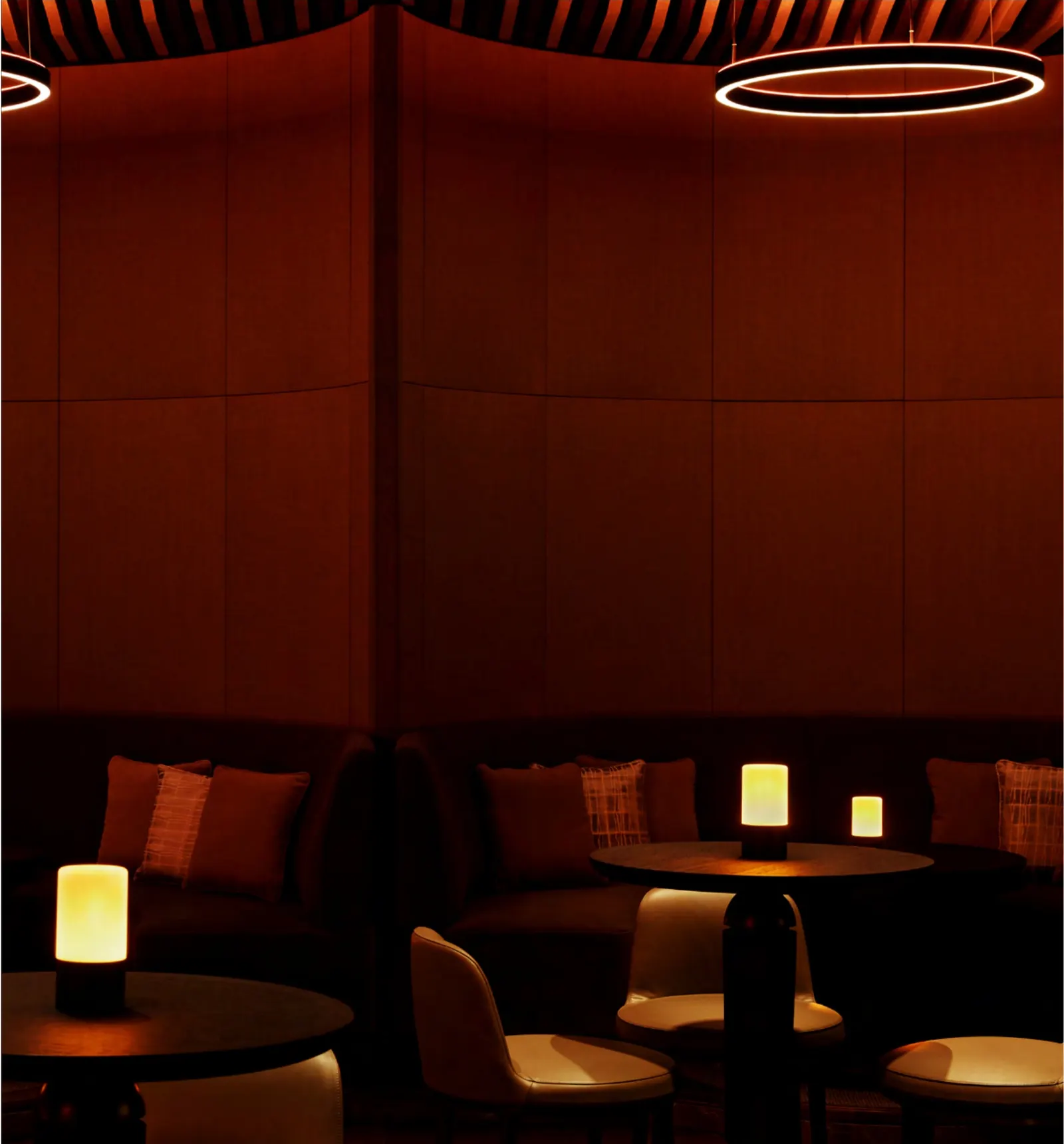 Warm, low-lit lounge with curved banquettes at Aman Club