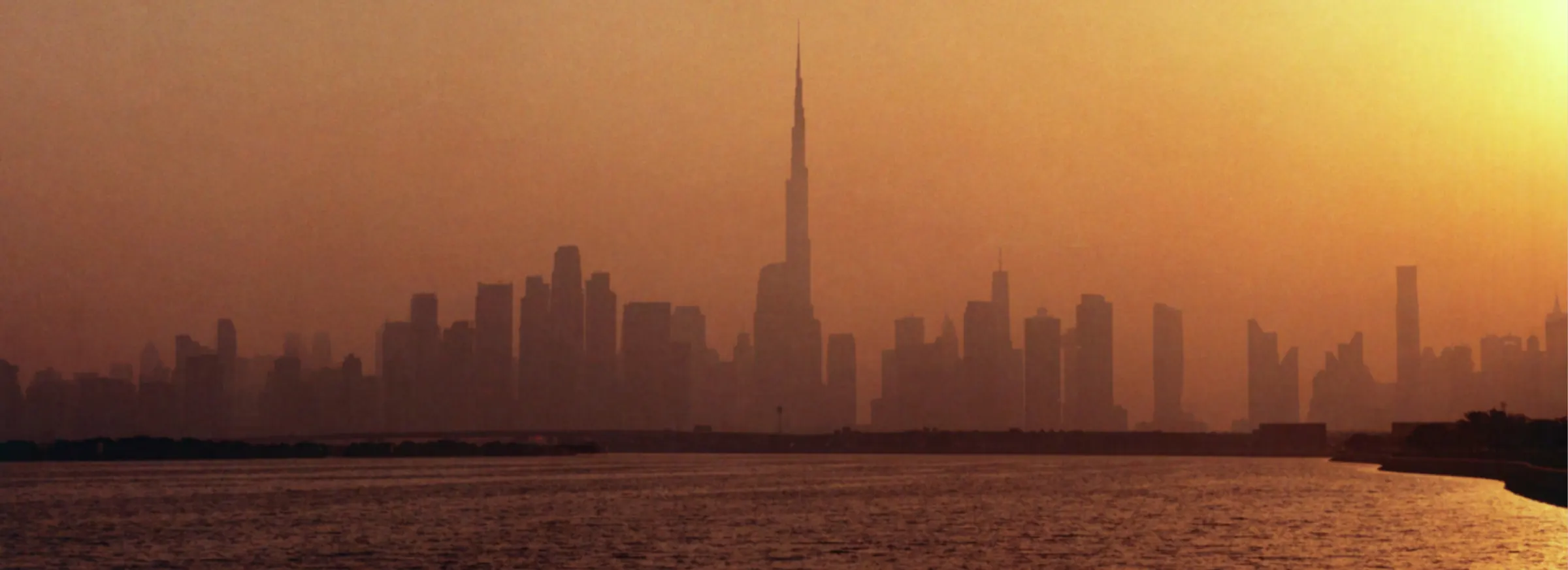 The Dubai skyline and Burj Khalifa at golden hour, seen across the water from Dubai Peninsula